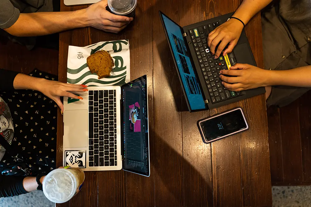 Overhead view of student laptops open on a table at Starbucks.