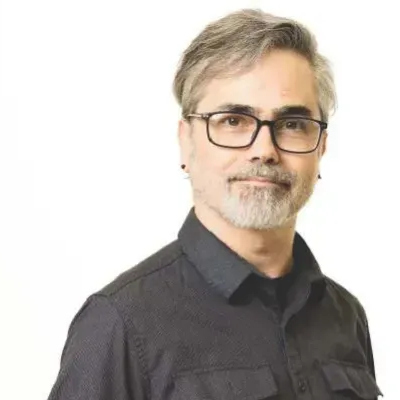 Jesse Koenig wearing glasses and a dark button-up shirt against a white background.