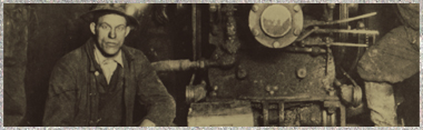 A Miner wearing a hard hat posing next to a large piece of machinery inside of a mine